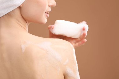 Kahverengi arka planda sabun çubuğu olan kadın, yakın plan.