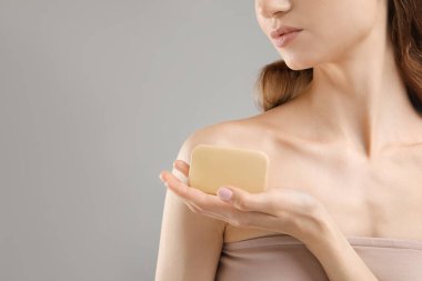 Gri arka planda sabun çubuğu olan kadın, yakın plan. Metin için boşluk