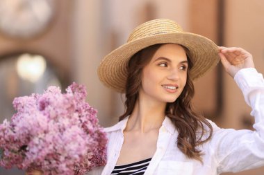 Gülümseyen kadın, arka planda bir demet leylak çiçeğiyle yakın plan,