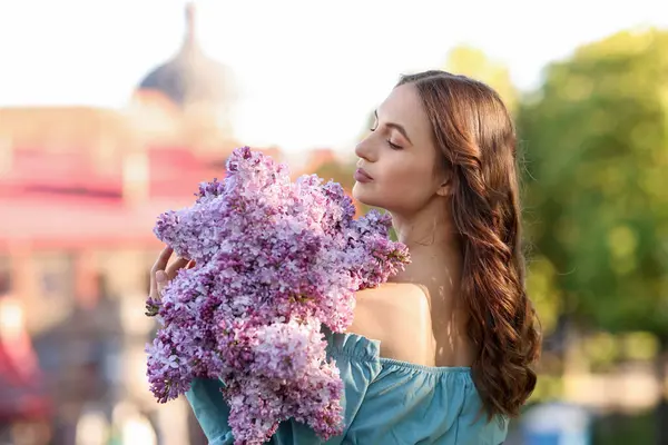 Güzel bir kadın ve açık havada bir demet leylak çiçeği.