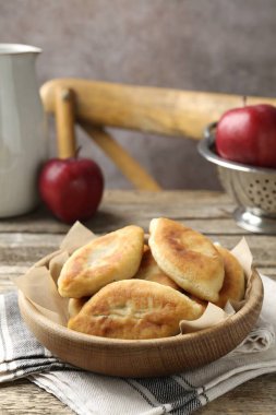 Lezzetli kızarmış pirinçler (doldurulmuş turtalar) ve ahşap masada elmalar, yakın plan.