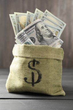 Üzerinde dolar banknotları olan para çantası. Gri ahşap masa, yakın plan.