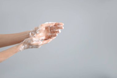 Açık gri arka planda ellerini sabunla yıkayan kadın, yakın plan. Metin için boşluk