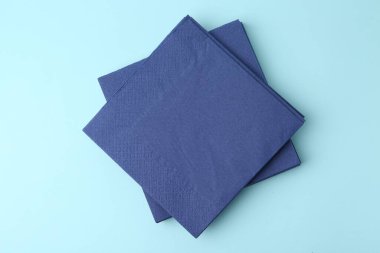 Açık mavi arkaplanda tek kullanımlık kağıt mendil yığını, üst görünüm