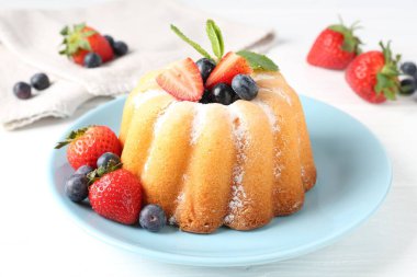 Beyaz ahşap masada pudra şekerli ve dutlu Lezzetli kek, yakın plan.