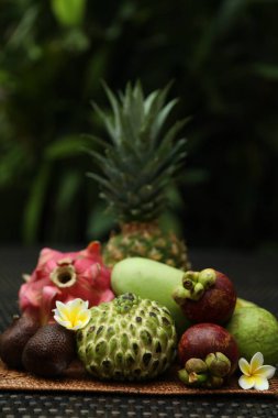 Açık havada hasır masada farklı tropikal meyveler.
