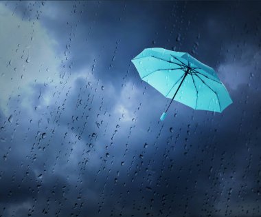 Açık mavi şemsiye kara bulutlu gökyüzünde uçuyor, ıslak pencereden bakıyor. Fırtınalı hava