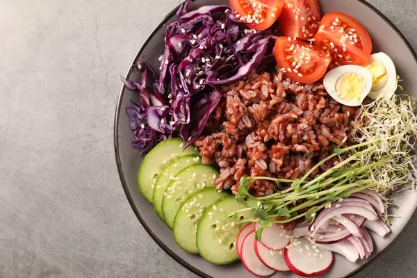 Gri masada kahverengi pirinçli lezzetli bir salata.