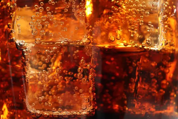 Arkaplan olarak buz küpleriyle kola tazeleniyor, makro görünüm