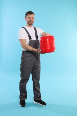 Açık mavi arka planda plastik kutu tutan adam.