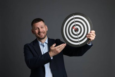 Hedef alınıyor. Dart tahtası ve gri arka planda oku olan bir adam.