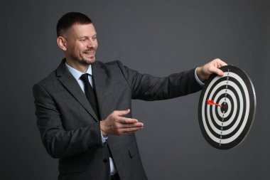 Hedef alınıyor. Dart tahtası ve gri arka planda oku olan bir adam.