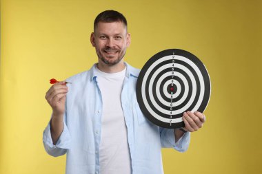 Hedef alınıyor. Sarı arka planda ok ve dart tahtası olan adam.