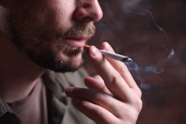 Arka planda sigara içen adam, yakın plan.