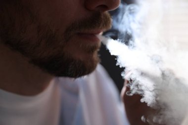 Arka planda sigara içen adam, yakın plan.