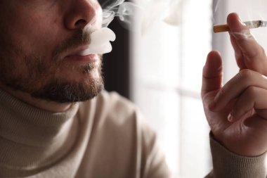 Arka planda sigara içen adam, yakın plan.