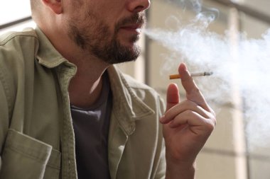 Arka planda sigara içen adam, yakın plan.