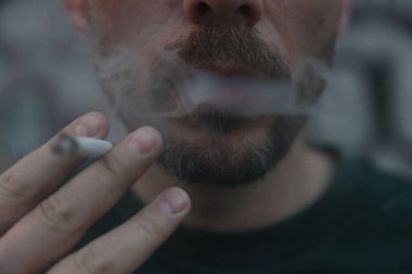 Arka planda sigara içen adam, yakın plan.