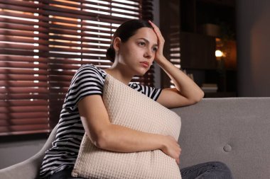 Depresyondaki kadın evdeki kanepede yastığa sarılıyor.