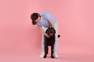 Hayvan eğitimi. Pembe arka planda sevimli köpeği olan bir kadın.