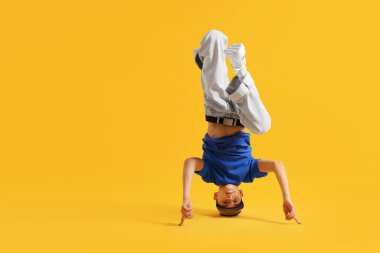 Şık giyinmiş çocuk turuncu arka planda dans ediyor, mesaj için yer var.