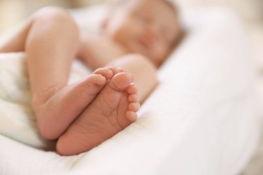 Küçük bebek evde yatakta uzanıyor, seçici bir odak noktası. Metin için boşluk