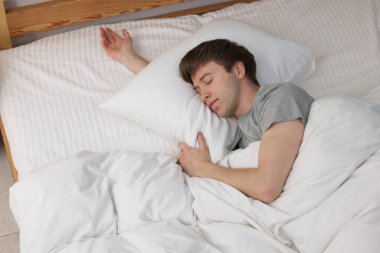 Genç adam yatağında uyuyor, yukarıda.