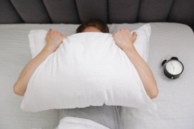 Yastık ve çalar saatle kaplı yorgun adam içeride, manzaranın üstünde.