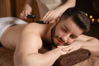 Adam spa salonunda taşlarla masaj yaptırıyor.