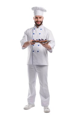 Üniformalı mutlu pastacı beyaz arka planda lezzetli ekinler tutuyor.