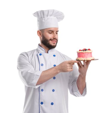 Üniformalı mutlu pastacı elinde beyaz arka planda böğürtlenli kek tutuyor.