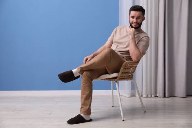 Yakışıklı adam evdeki sandalyede dinleniyor.