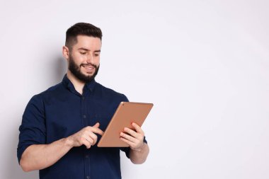 Beyaz arkaplanda tablet kullanan yakışıklı adam, metin için boşluk