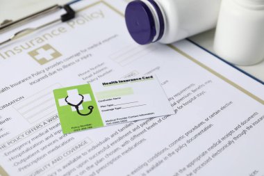 Sağlık sigortası kartı, sigorta ve tıbbi şişeler beyaz masada, yakın plan.