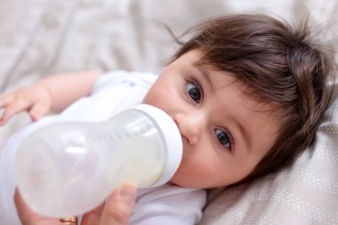 Babası bebeğini evde şişeyle besliyor, yakın plan.