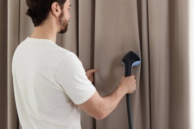 Evde buharlı perdeleri olan bir adam.