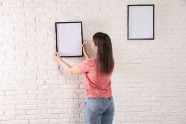 Beyaz tuğla duvara boş çerçeveler asan kadın, arka plan