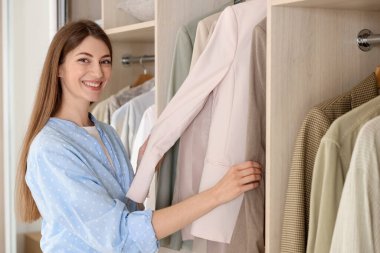 Gülümseyen moda tasarımcısı stüdyoda kıyafet seçiyor.