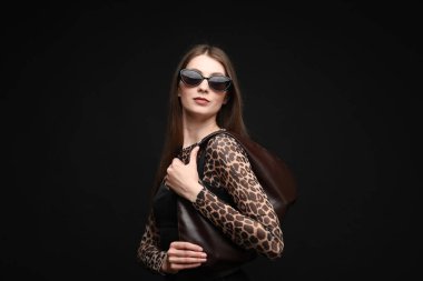 Siyah arka planda şık giyinmiş güzel bir kadının moda portresi.