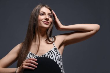Gri arka planda şık giyinmiş güzel bir kadının moda portresi.