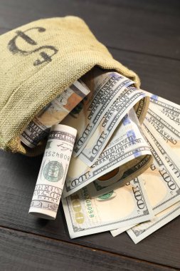 Üzerinde dolar banknotları olan para çantası. Gri ahşap masa, yakın plan.