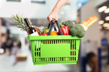 Süpermarkette elinde farklı gıda ürünleri olan bir adam var.