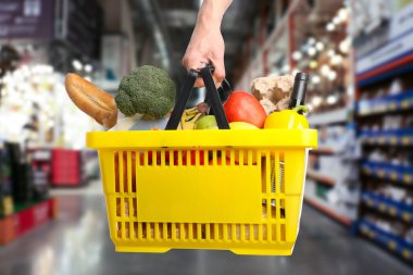 Süpermarkette elinde farklı gıda ürünleri olan bir adam var.