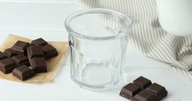 Beyaz ahşap masada lezzetli çikolatalı sütü cama dökerek.