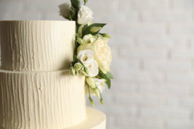 Beyaz arka planda çiçeklerle süslenmiş lezzetli düğün pastası, yakın plan. Metin için boşluk