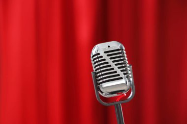 Kırmızı perdeye karşı bir klasik mikrofon, yakın plan. Metin için boşluk