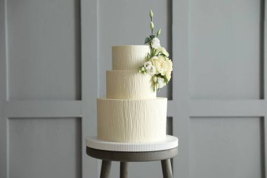 İçerideki masada çiçeklerle süslenmiş nefis düğün pastası.