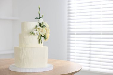 İçerideki ahşap masada çiçek desenli nefis düğün pastası, mesaj için yer.