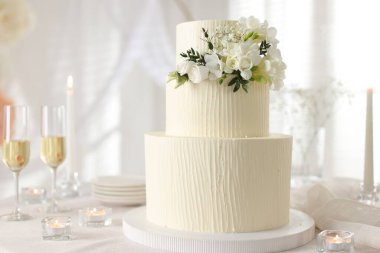 Çiçek desenli nefis düğün pastası ve kapalı bir masada şampanya bardakları.