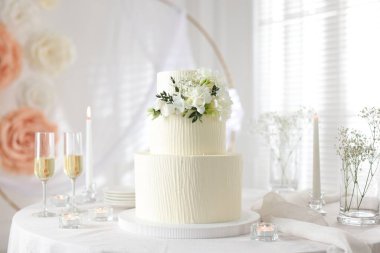 Çiçek desenli nefis düğün pastası ve kapalı bir masada şampanya bardakları.